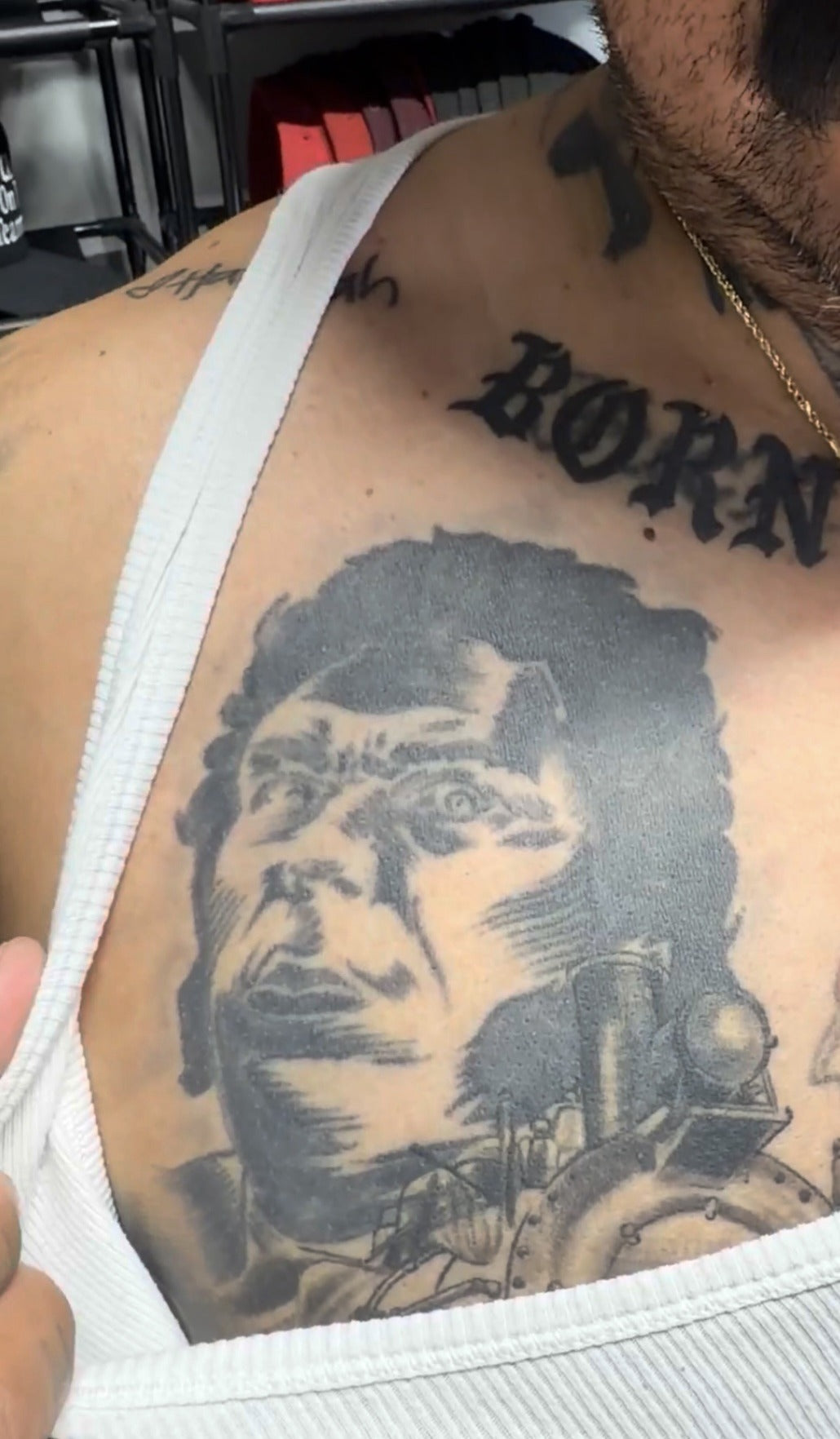 Tattoo on a person's shoulder, wearing a white tank top.