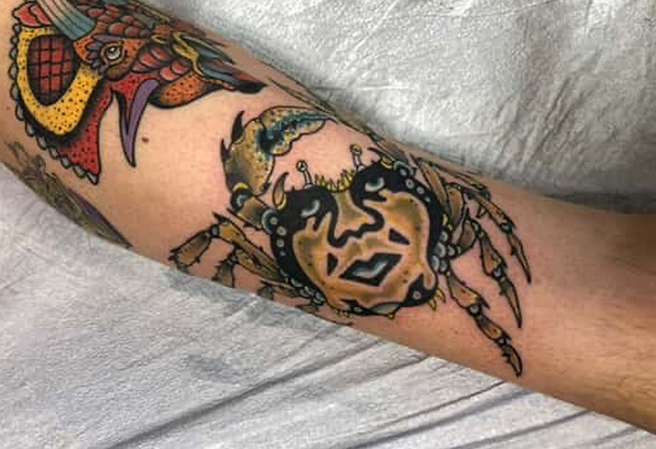 Colorful crab tattoo on a person's arm with a neutral background