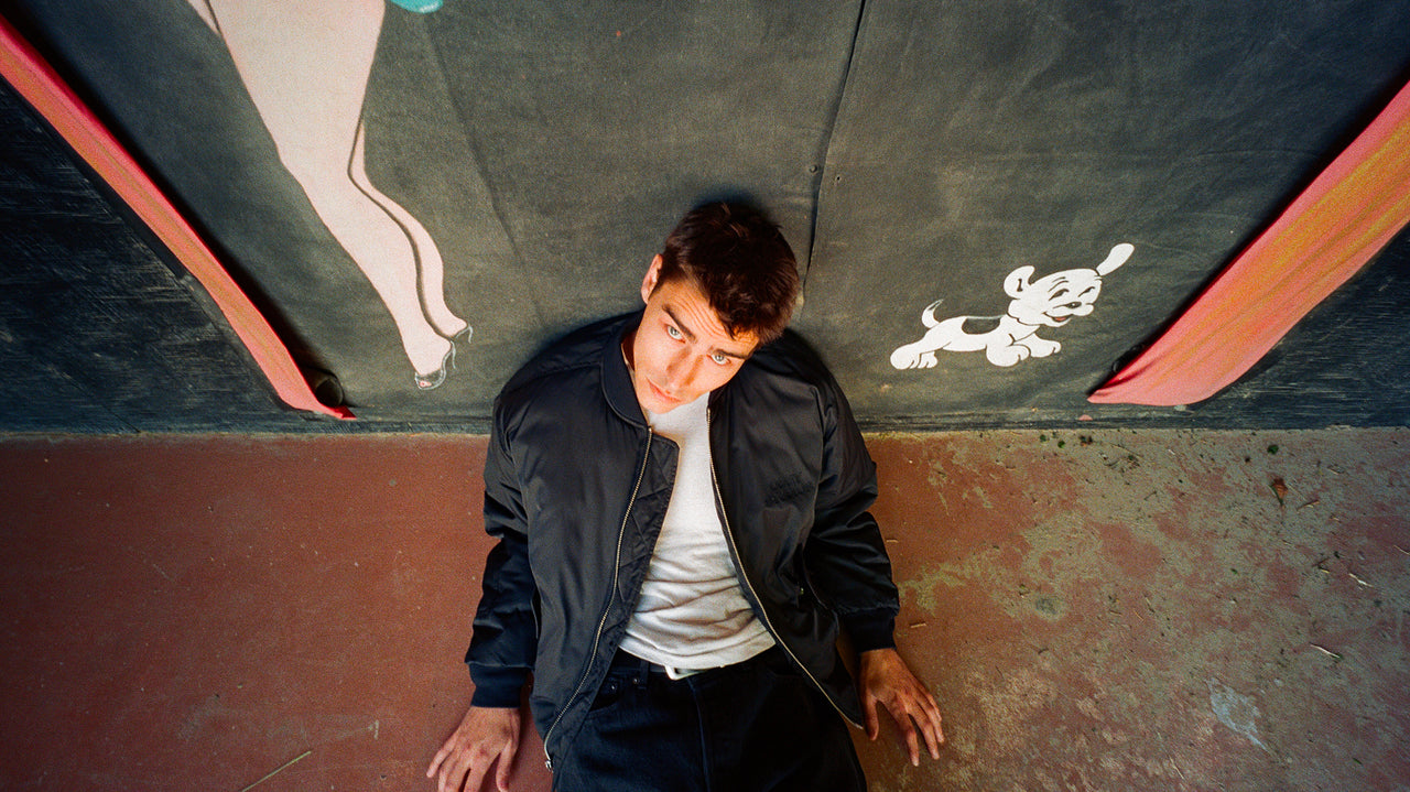 Person sitting on a concrete surface with a mural in the background