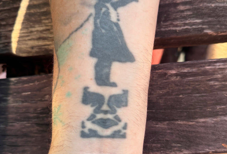 Tattoo of a child holding a sign on a person's arm with a wooden background