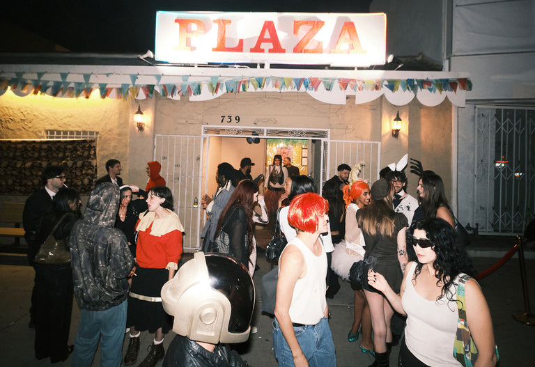 Group of people in costumes outside a building with 'Plaza' sign