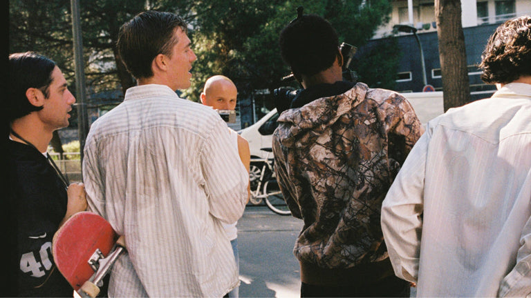 Group of people standing on a street with trees and buildings in the background