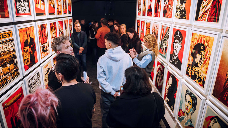 People viewing artwork at an exhibition with colorful prints on the walls.