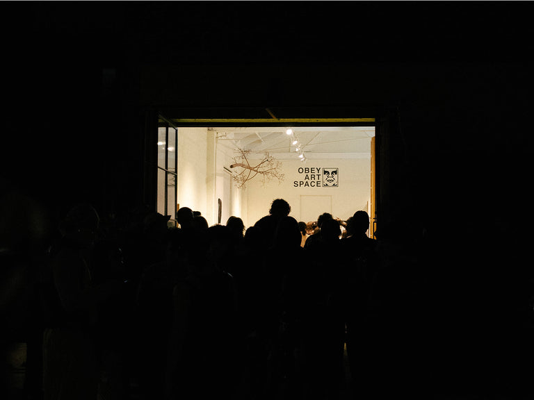 People silhouetted against a window with 'Obey' and 'Art My Space' displayed inside.