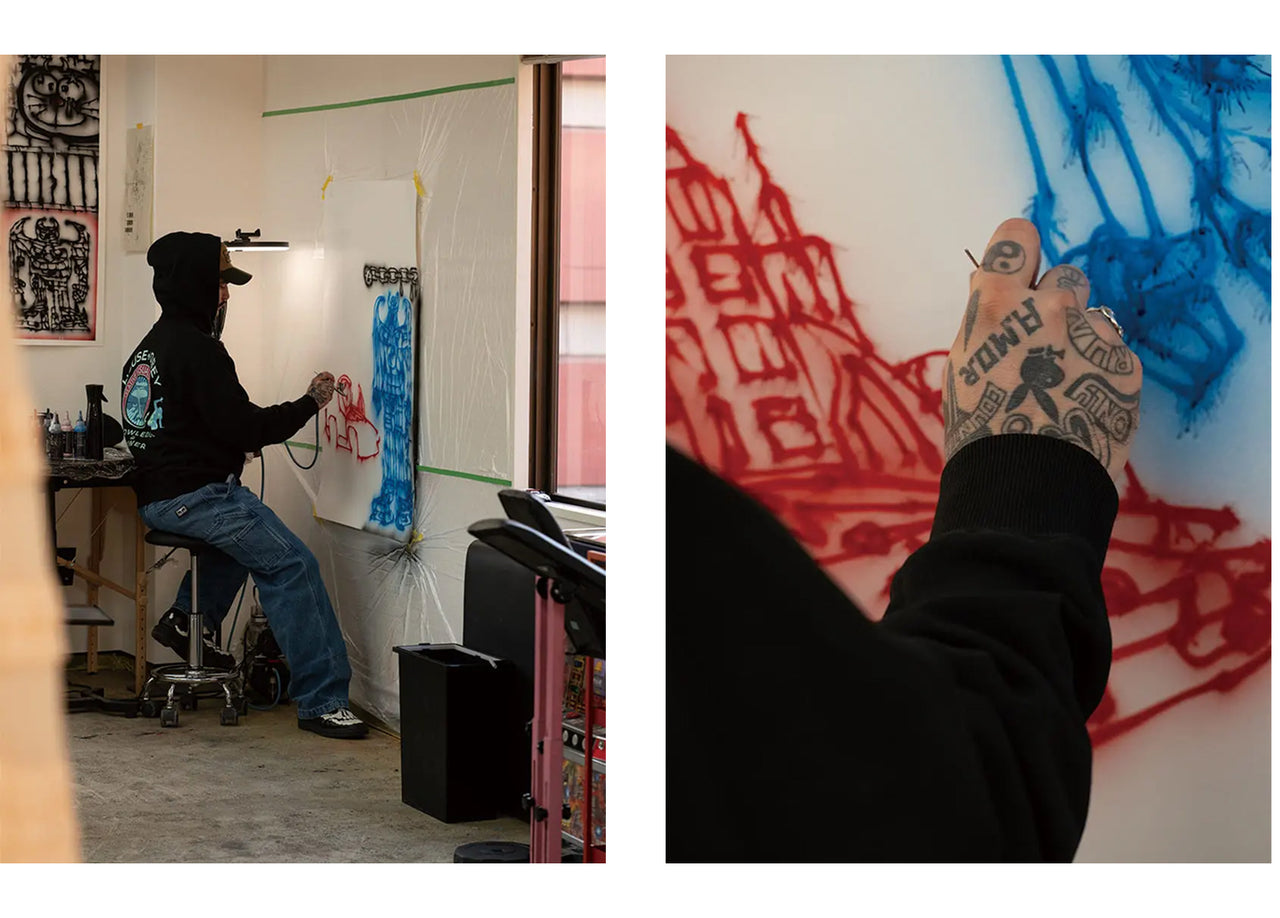 Person working on a large drawing in an art studio with close-up of tattooed hand.