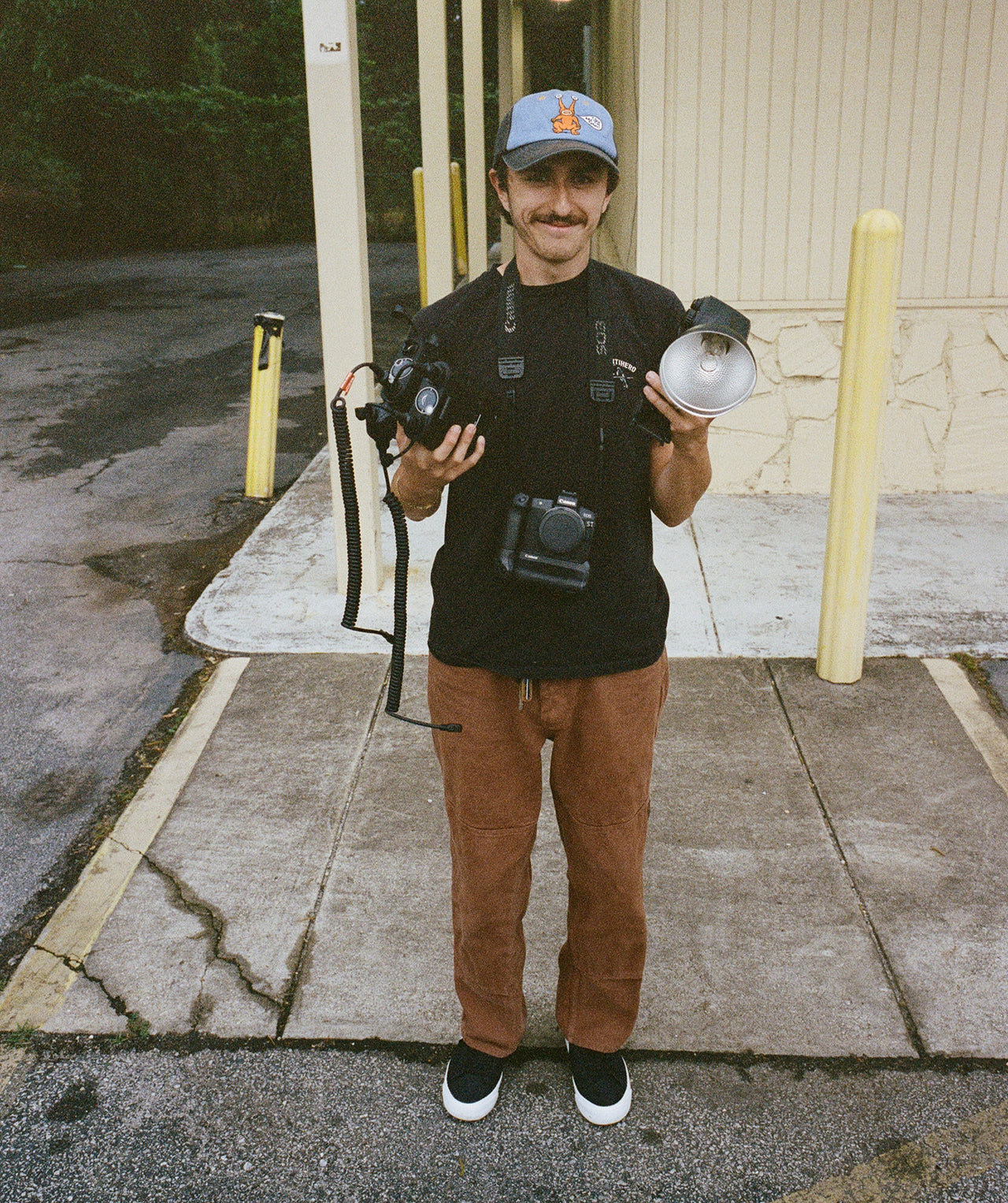 Person holding camera equipment outdoors on a sidewalk