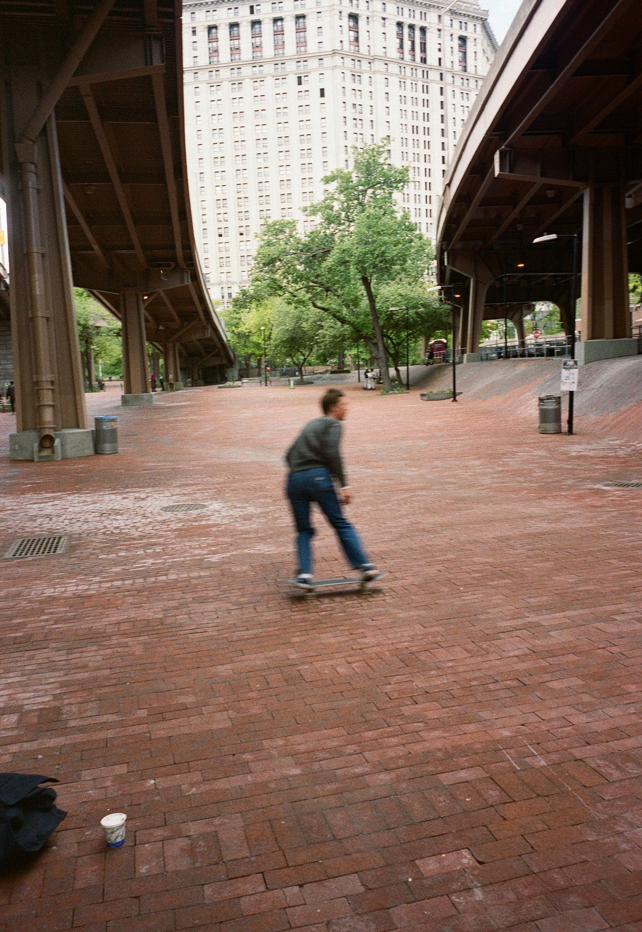 Person skateboarding on a brick path with a large building in the background
