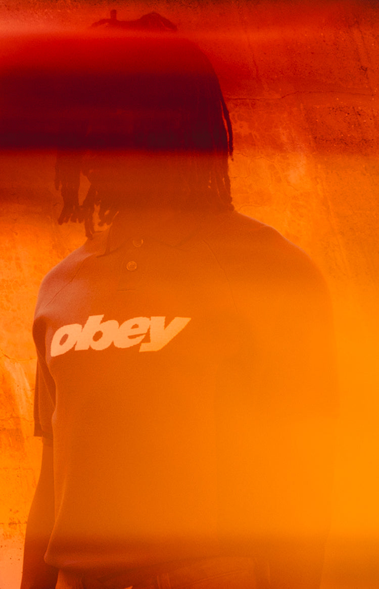 Person wearing a hoodie with 'obey' logo in a red-orange hue