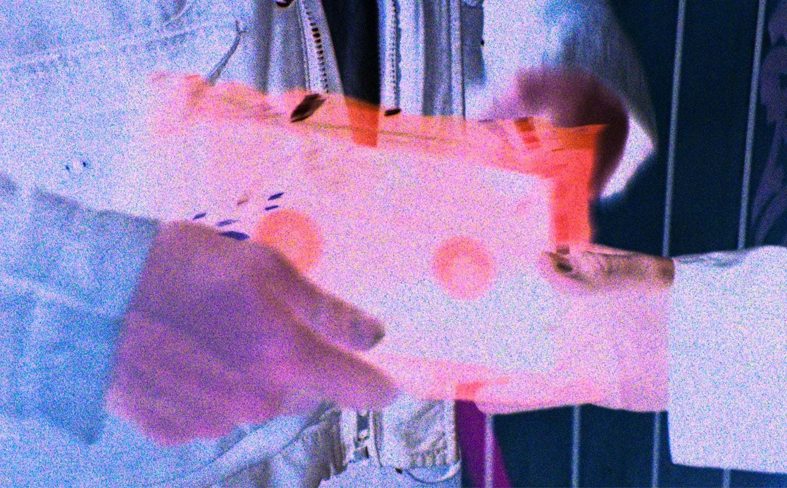 A close-up, negative shot of a person in a jacket holding a vhs.