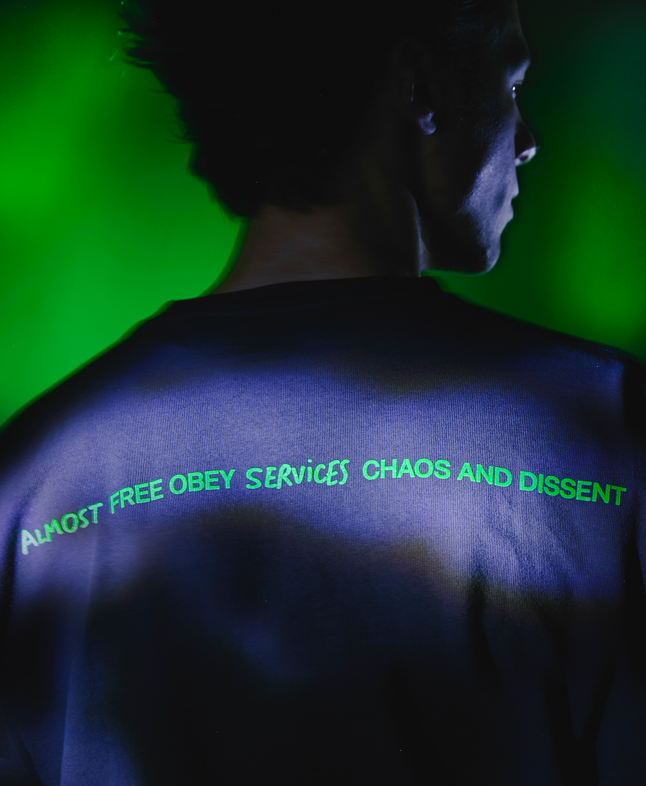 Person with text on back glowing in dark against green screen