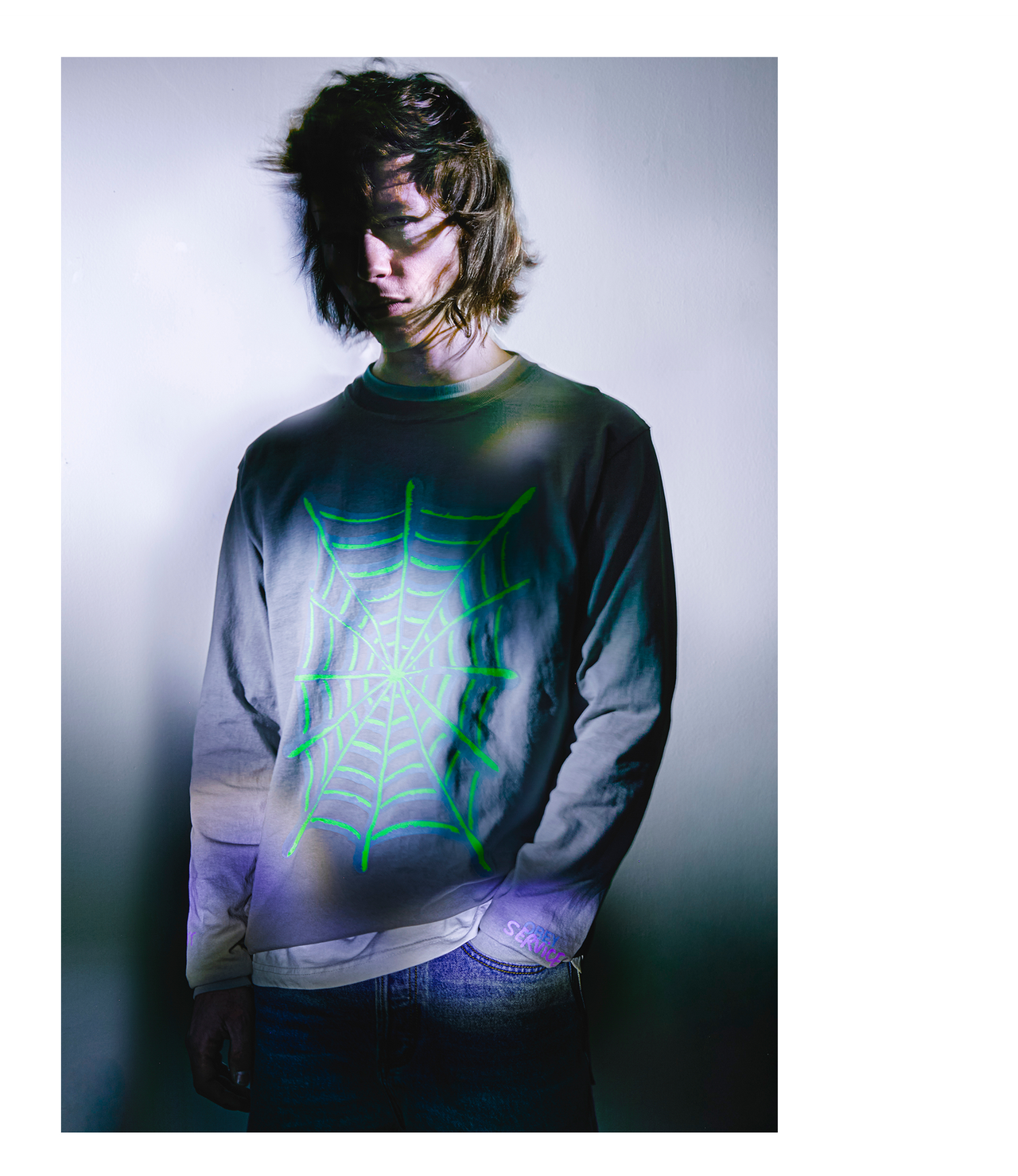 Person wearing a shirt with a glowing green spider web design on a dark background