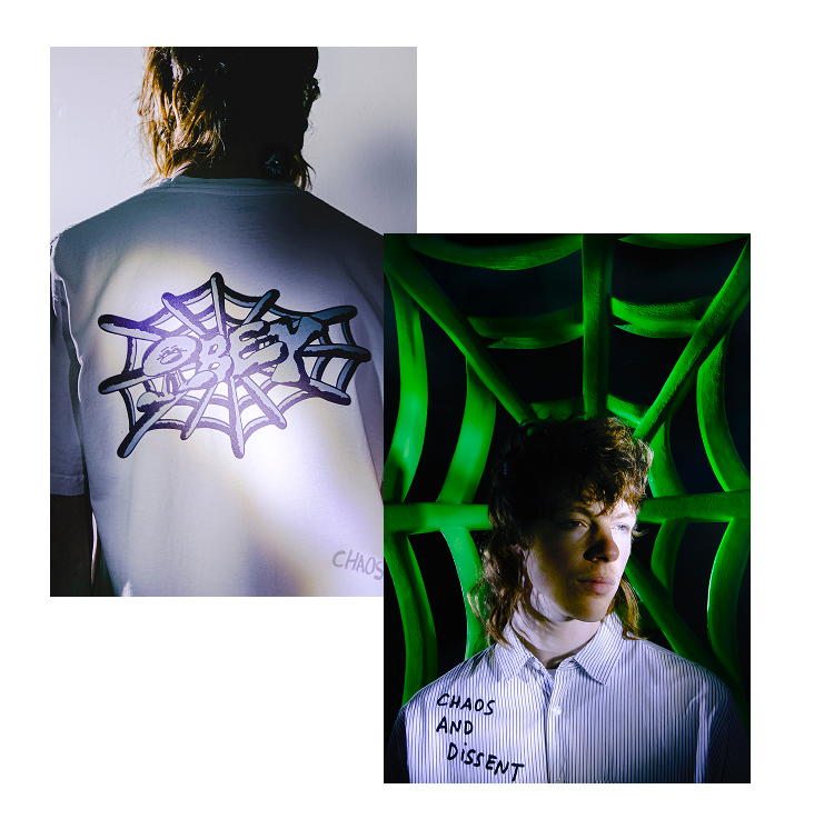 Person with spider web design on shirt and text 'Chaos and Dissent' in front of green abstract background