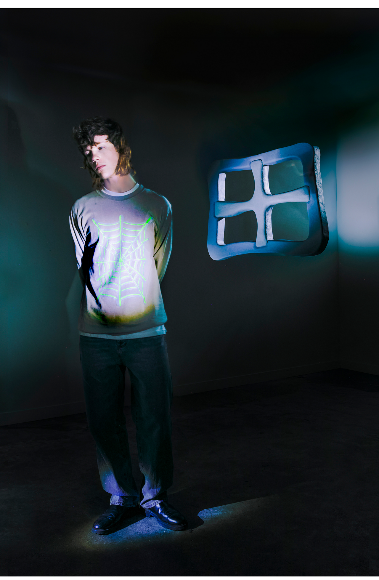Person wearing a glowing shirt in a dark room with a window in the background