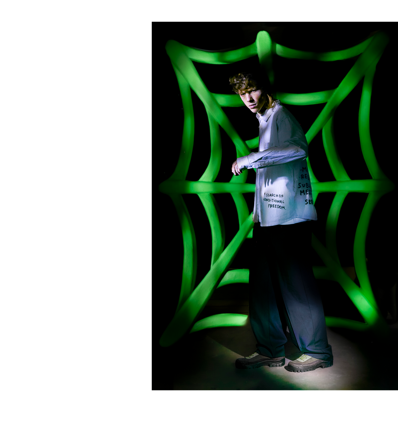 Person standing in front of a green, wavy light sculpture