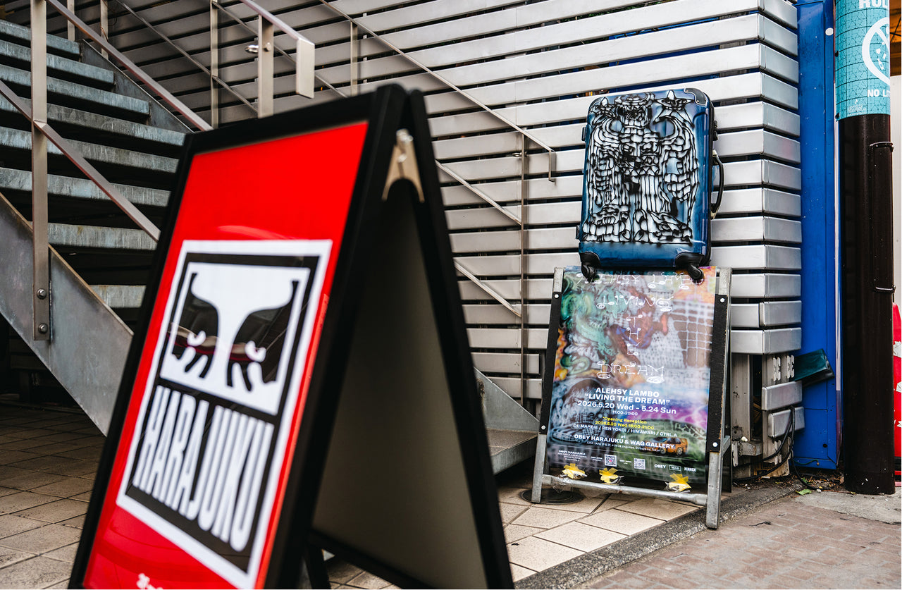 Outdoor setting with a red and black sign featuring obey logo and art flyer.