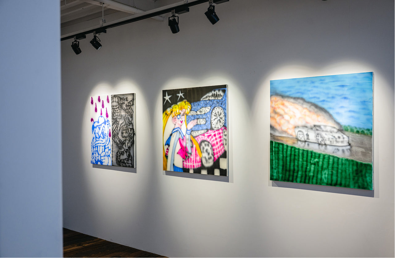 Artistic paintings displayed on a wall in an art gallery.